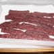 Deer jerky all done and cooling down on paper towels. You can dab the shiny grease spots off to help it dry and cool.