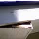 Block secured; the screw head is visible against the soffit board. A second screw, unseen in this perspective, secures the right end as well.