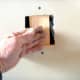 Using a screw as a handle to hold the backing in place while screwing through the existing drywall.