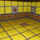 Yellow talavera tile kitchen countertop with border and single pattern tiles.