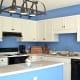 Cabinets painted white, backsplash and cornice over cabinets blue.Stove hood repainted glossy black.