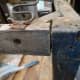 Widening the gap at the top of the chair with a wooden mallet, where any of the joints are loose, in preparation for gluing.