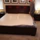The mattress is unrolled and placed into the correct position after the outer layer of plastic is cut and removed. The inner plastic remains keeping the mattress compressed.
