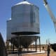 The next morning, a crane operator lifts the bin so the last ring may be built, then lifts it onto a hopper. Once the bin is secured to the hopper, his job is done.