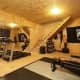 A rustic home gym with plywood ceiling and walls and black flooring