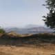 The overlook by the left side of the dirt road. Take position here.