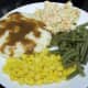 Vegetable plate with potatoes and gravy, corn, green beans, and slaw