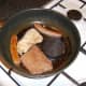 The Lorne sausage and black pudding are added to the pan after the pork has been turned.