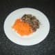 Grated carrot and meat pieces are added to soup.