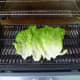 Overlap the wet romaine leaves on the grill.