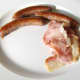 Sausages and bacon are plated for full Welsh breakfast.