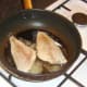 Sea bream fillets are added to frying pan skin sides down