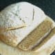 Slice of wheat, spelt and rye bread is cut to serve with kangaroo and vegetables