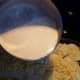 Pour the hot cream over the potatoes.