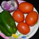 The vegetables used for making tomato and capsicum curry.