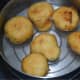 Step six: Take them out from the oil and drop into a bowl of lukewarm water. Set aside for about 12 minutes. The vadas will absorb the water.