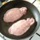 Seasoned pork fillets are put on to fry in a little oil.