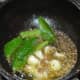 Step three: To make the seasoning, add ghee or oil, garlic cloves, asafetida powder, curry leaves, and pepper powder to a pan. Saute until the garlic becomes brownish. Turn off the heat and transfer it to the vessel containing moong dal rasam.