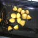 Boiled and cooled turmeric potatoes are turned in hot roasting oil
