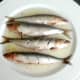 Slashed sardines are turned in garlic oil