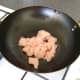 Dice the chicken and add it to a hot wok with sunflower oil.