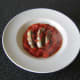 The sardines and tomato sauce are transferred to a serving plate with a large slotted spoon