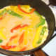 Beaten duck eggs are poured over bell peppers