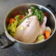 Vegetables, herbs and seasonings are added to pot with chicken