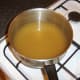 Lamb stock is brought to a simmer in saucepan