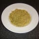Spaghetti and green pesto sauce is laid in the bottom of a deep serving plate