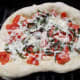 The pizza can be placed directly on the grill or on a pizza stone.