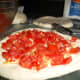 Put tomatoes on the pizza dough.