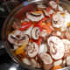 Cover the cooked chicken with peppers and onions. Add one cup of sliced mushrooms. Cover and simmer for about 5 minutes.