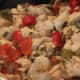 Chicken cooking with cherry peppers, garlic, scallions and mushrooms.