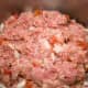 Thoroughly mix the meats, seasonings, uncooked rice, onion, and petite tomatoes together with your hands.