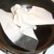 Wiping the excess oil and food remnants from the frying pan before frying the egg