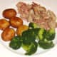 Roast rabbit saddle meat is plated with roast potatoes and broccoli