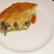 A piece of pastry is laid on top of the rabbit and pork pie filling