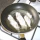 Flounder fillets are added to frying pan