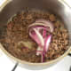 Red onions are added to browned mince