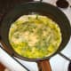 Eggs and herb are added to oil in frying pan