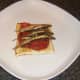 Grilled sprats are laid on spicy tomato sauce