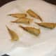 Deep fried battered sprats are drained on kitchen paper