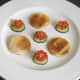 Toast circles are plated with tomato and cucumber.