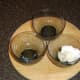 Small glass bowls are oiled for receiving cracked quail eggs.