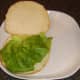 Lettuce bed is formed on bread roll.