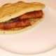 Second mini naan bread is laid on top of spicy sausages and beans