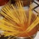 Spaghetti is added to turmeric spiced water