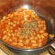Dried oregano is added to baked beans in tomato sauce