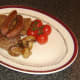 Tomatoes and mushrooms are plated with beef fry up components.